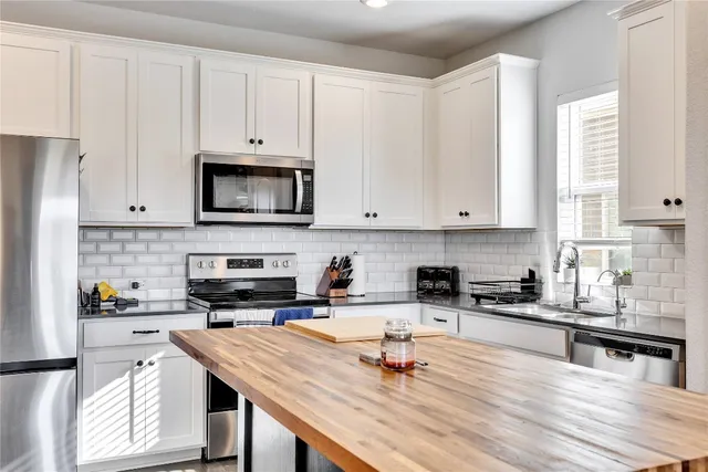 a kitchen with stainless steel appliances granite countertop a stove a sink a microwave and wooden cabinets