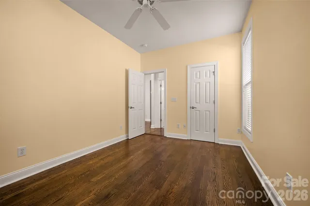 an empty room with wooden floor and a ceiling fan
