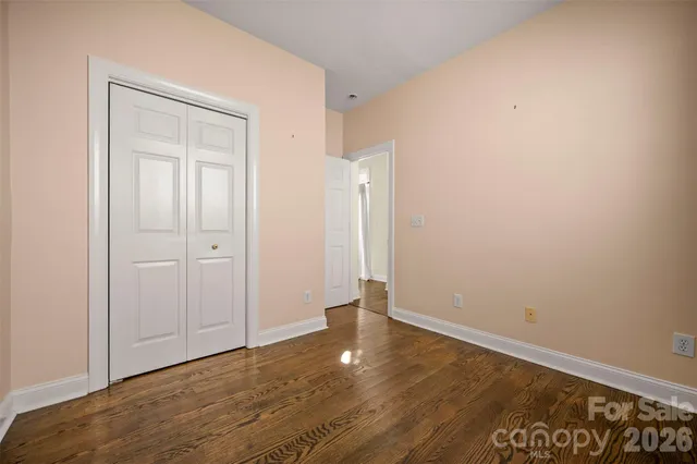 a view of an empty room with wooden floor and closet