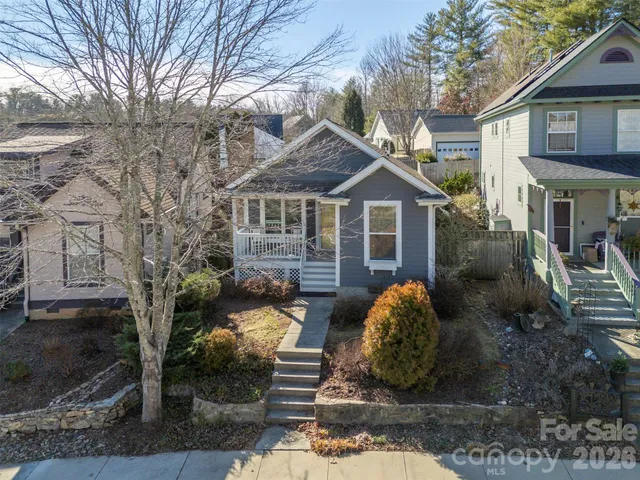 a view of a white house with large windows and a small yard