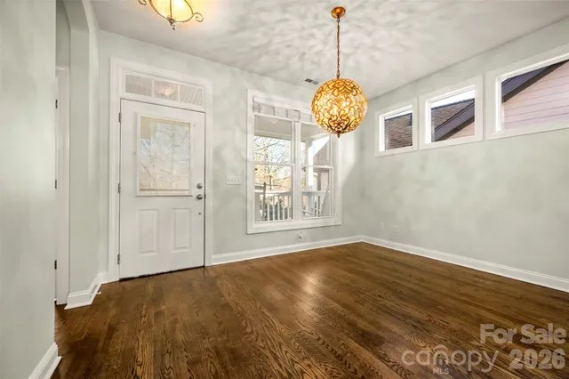 a view of an empty room with window and wooden floor