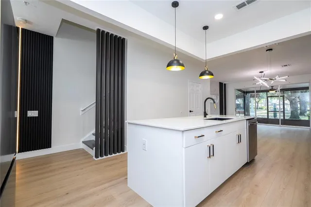 a kitchen with stainless steel appliances granite countertop a sink a stove and a wooden floor