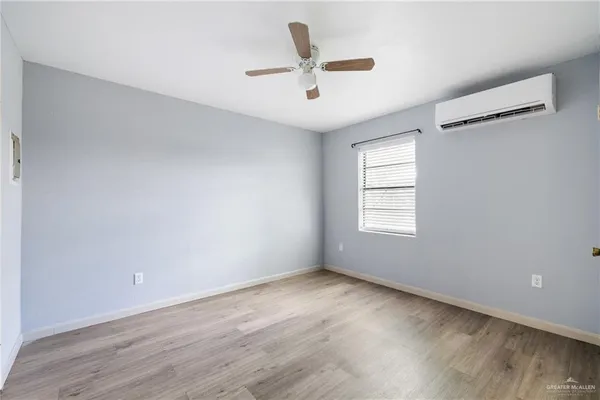 an empty room with wooden floor ceiling fan and windows