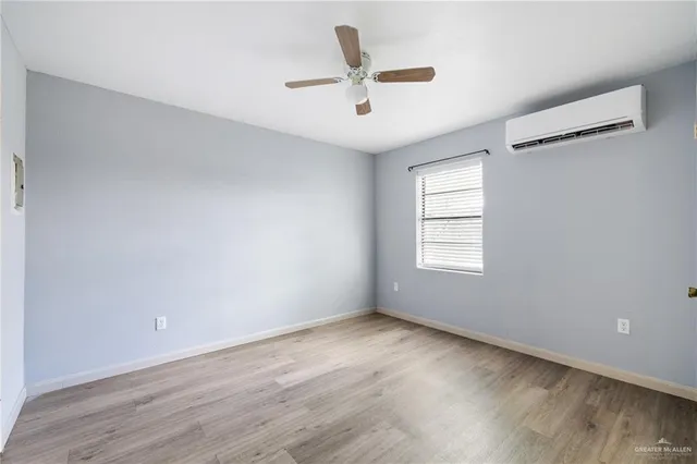 an empty room with wooden floor ceiling fan and windows