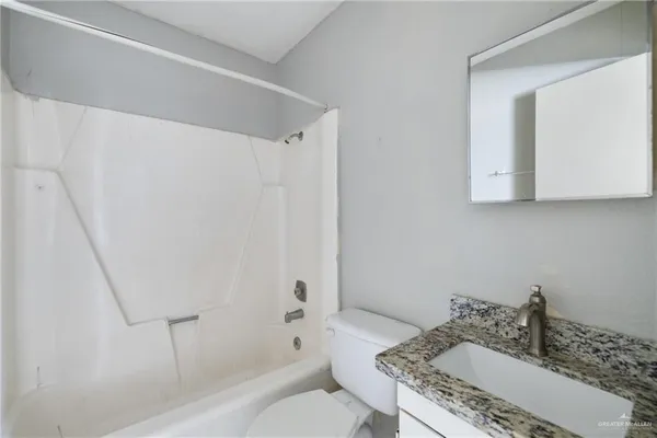 a bathroom with a granite countertop sink a toilet and shower