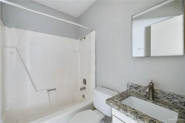 a bathroom with a granite countertop sink a toilet and shower