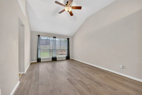 an empty room with wooden floor closet and windows
