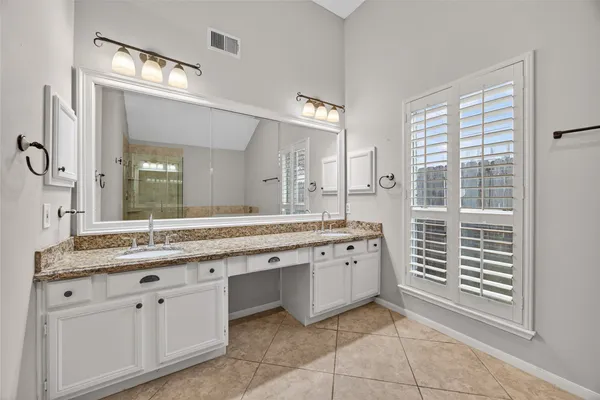 a spacious bathroom with a granite countertop sink and a mirror