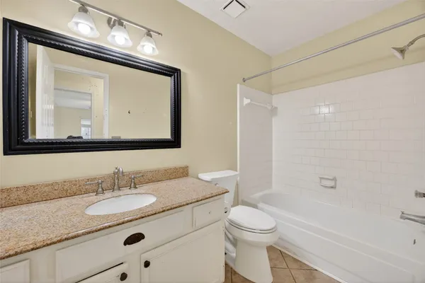 a bathroom with a granite countertop sink a toilet a mirror and shower