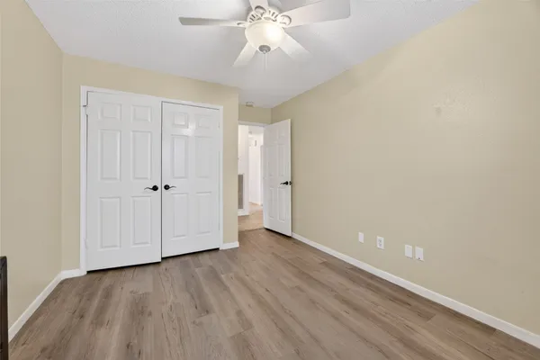 an empty room with a ceiling fan and wooden floor