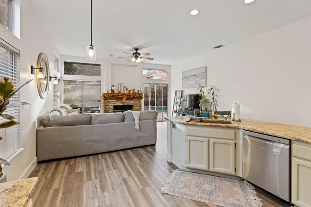 a living room with stainless steel appliances granite countertop furniture a fireplace a flat screen tv and a window