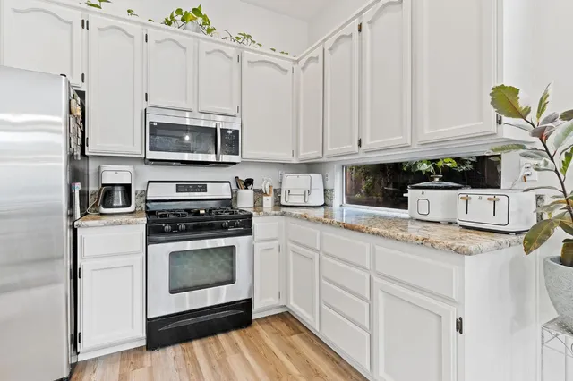 a kitchen with granite countertop white cabinets stainless steel appliances and sink