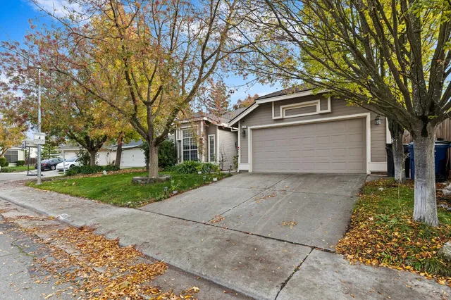 a front view of a house with a garden and trees