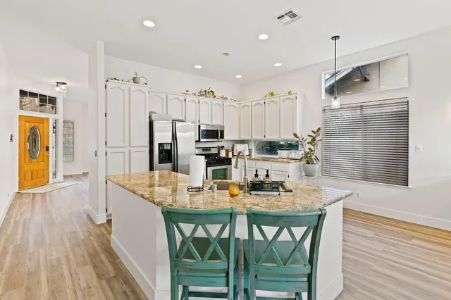a dining room with stainless steel appliances kitchen island granite countertop furniture and wooden floor