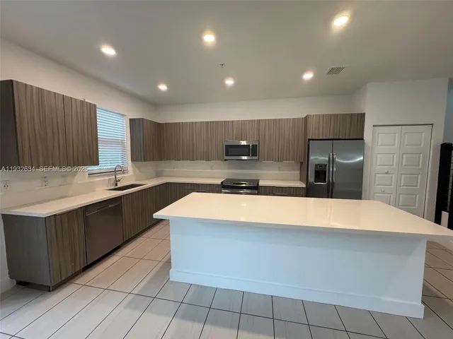 a large kitchen with stainless steel appliances a sink dishwasher stove and refrigerator
