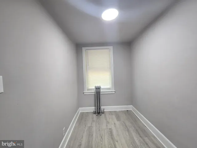 a view of empty room with window and wooden floor