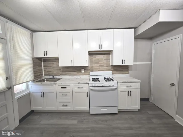 a kitchen with stainless steel appliances granite countertop a stove a sink and white cabinets