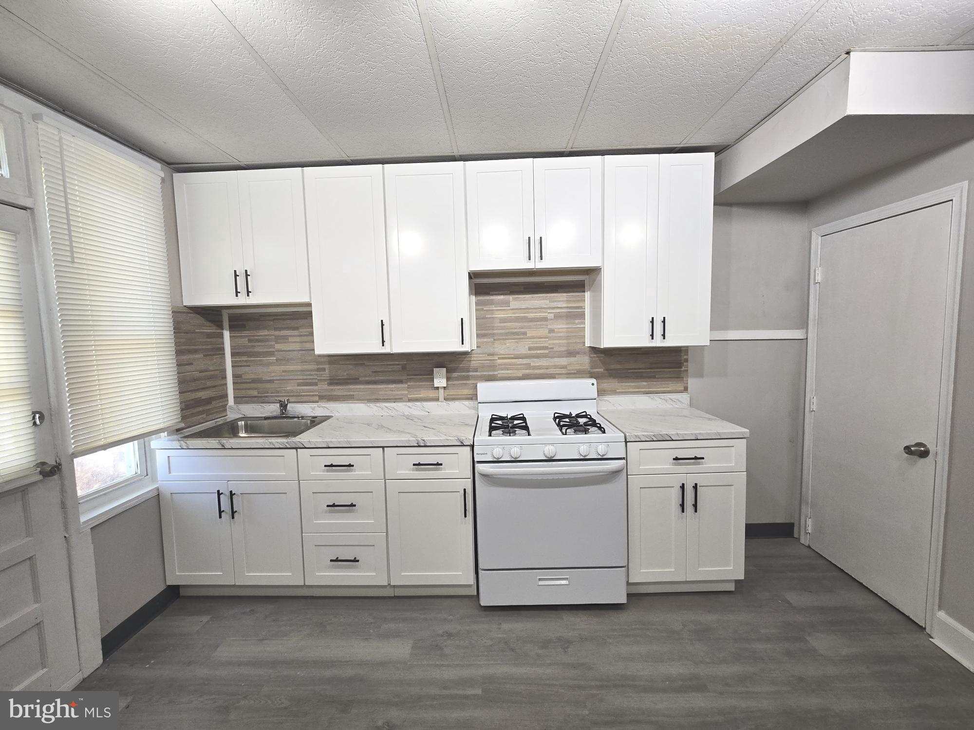 2642 South 67th Street Philadelphia, PA 19142 - Photo 6 of 23 a kitchen with stainless steel appliances granite countertop a stove a sink and white cabinets