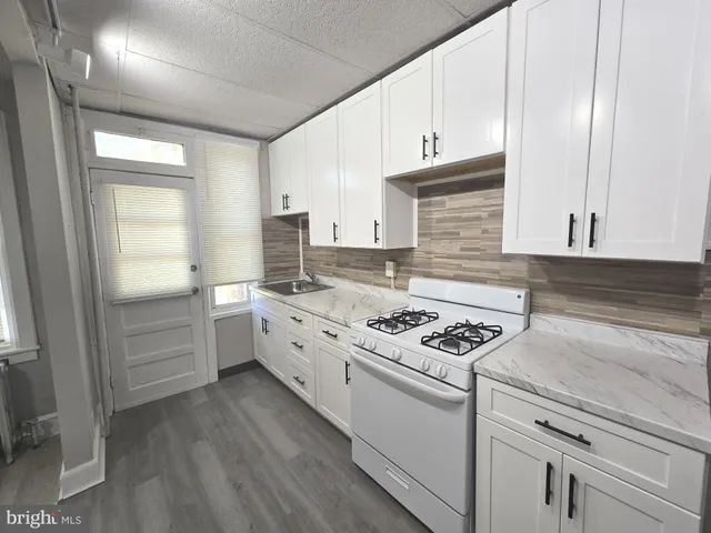 a kitchen with granite countertop a stove sink and cabinets