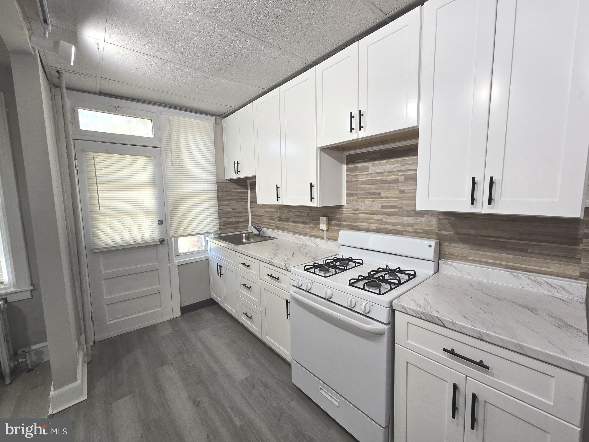 2642 South 67th Street Philadelphia, PA 19142 - Photo 7 of 23 a kitchen with granite countertop a stove sink and cabinets