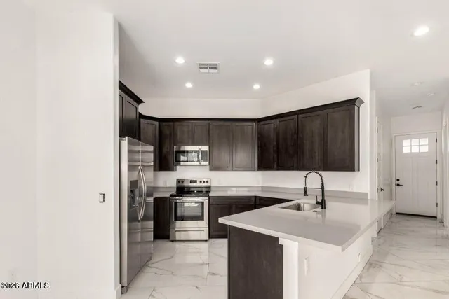 a kitchen with stainless steel appliances kitchen island sink refrigerator and cabinets