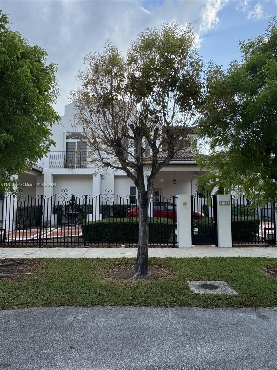 a front view of a house with a garden and tree