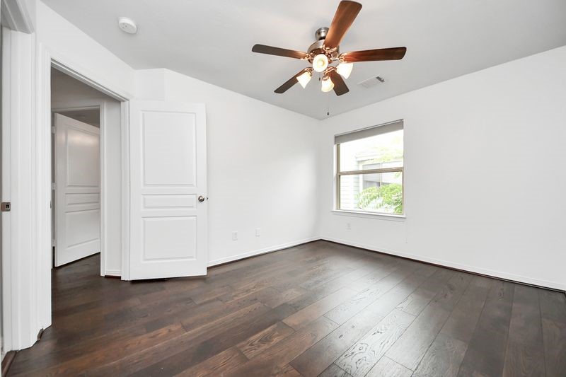 4222 Drake Street Houston, TX 77005 - Photo 24 of 28 an empty room with wooden floor chandelier fan and windows