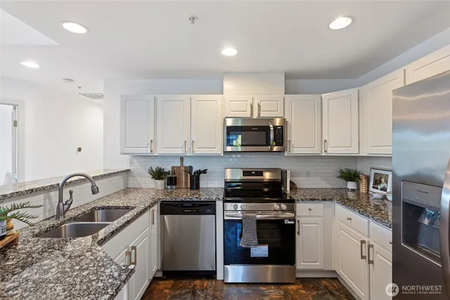 a kitchen with stainless steel appliances granite countertop a sink a stove top oven a counter space and cabinets
