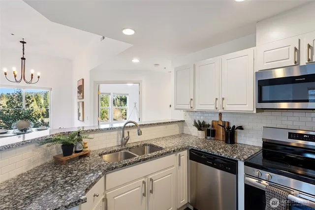 a kitchen with granite countertop a sink a stove and cabinets