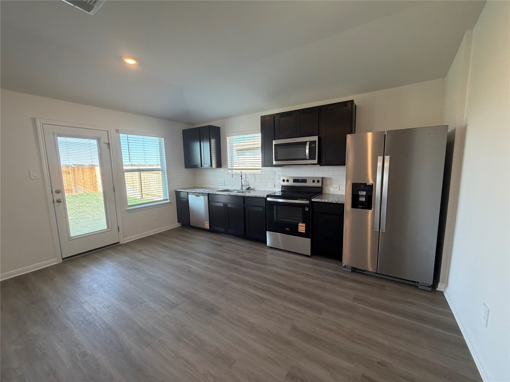 121 Honey Bee Road Jarrell, TX 76537 - Photo 4 of 10 Kitchen with appliances with stainless steel finishes, light countertops, decorative backsplash, dark wood-style flooring, and lofted ceiling