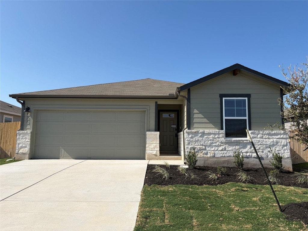 121 Honey Bee Road Jarrell, TX 76537 - Photo 9 of 10 Ranch-style house featuring concrete driveway, an attached garage, and stone siding