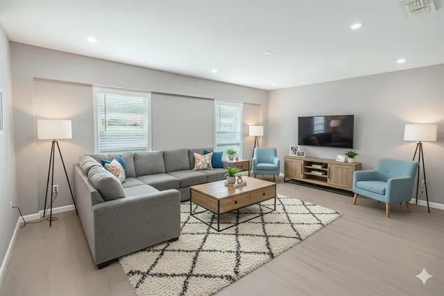 a living room with furniture a flat screen tv and a window