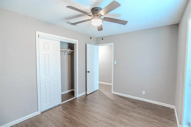 an empty room with wooden floor and ceiling fan