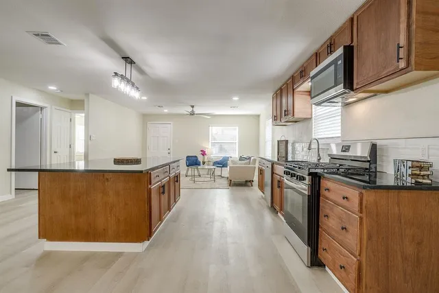 a large kitchen with stainless steel appliances granite countertop a stove and a sink