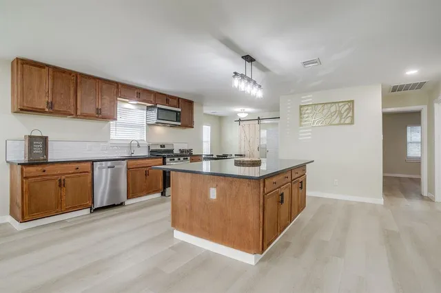 a large kitchen with stainless steel appliances granite countertop a sink and cabinets