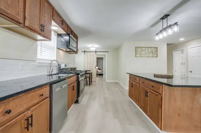 a kitchen with stainless steel appliances granite countertop a large counter top and wooden floor
