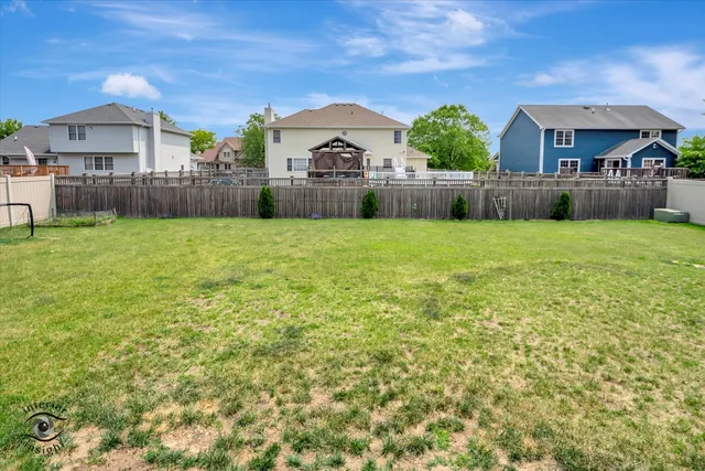 a white house that has a small yard and couches chairs with wooden fence