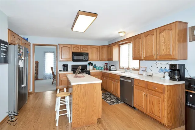 a kitchen with stainless steel appliances granite countertop a refrigerator a stove top oven a sink dishwasher and white cabinets with wooden floor