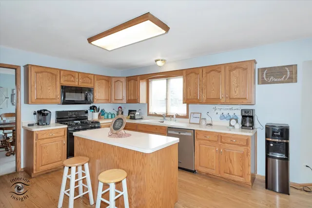 a kitchen with stainless steel appliances granite countertop a stove top oven a sink dishwasher a dining table and chairs with wooden floor