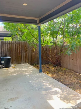 a view of a backyard with large trees and wooden fence