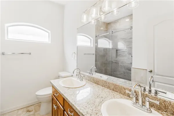 a bathroom with a granite countertop sink a toilet and a mirror