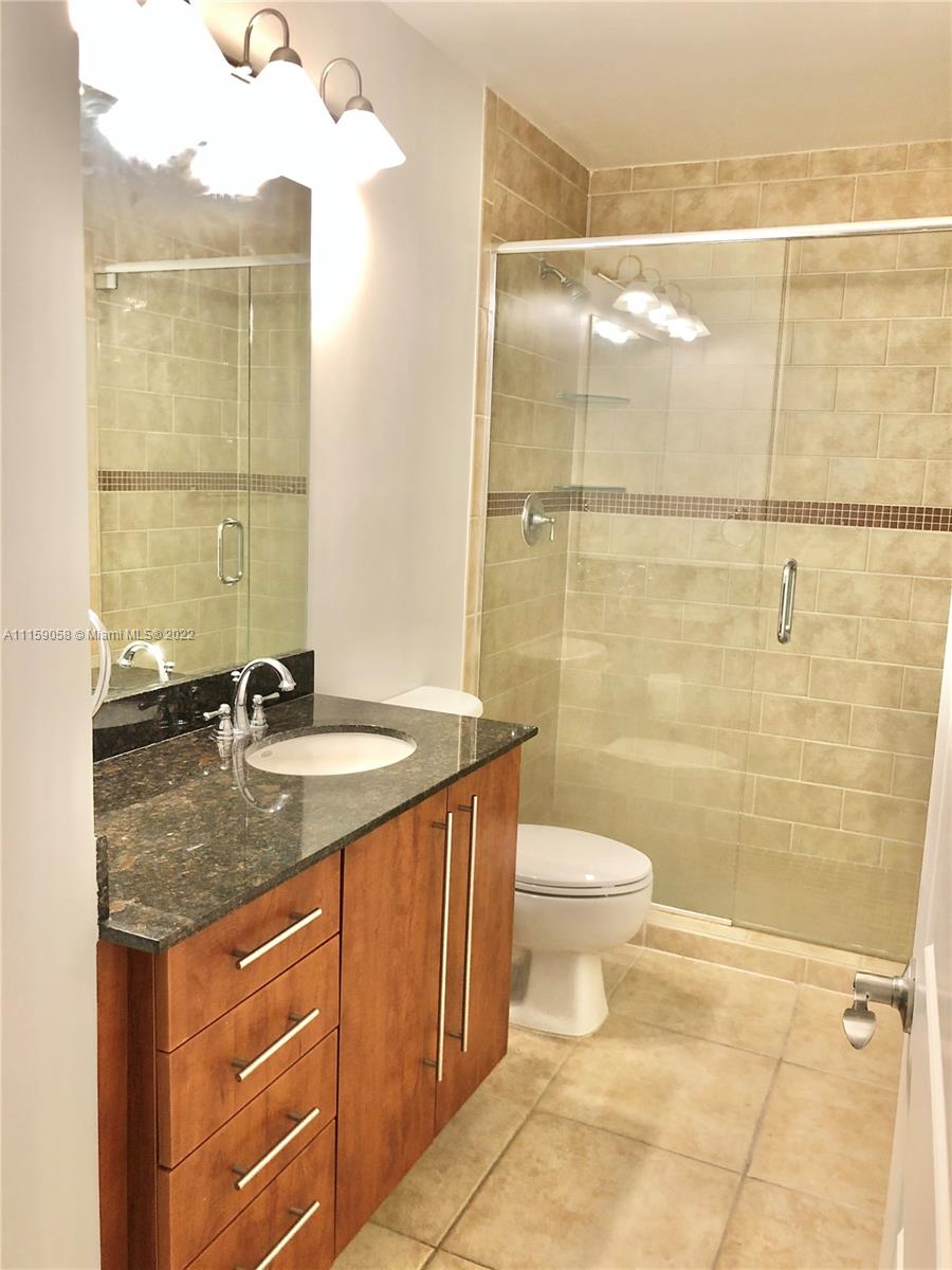7371 Southwest 90th Street, Unit TH106S Miami, FL 33156 - Photo 15 of 25 a bathroom with a granite countertop sink a toilet and shower
