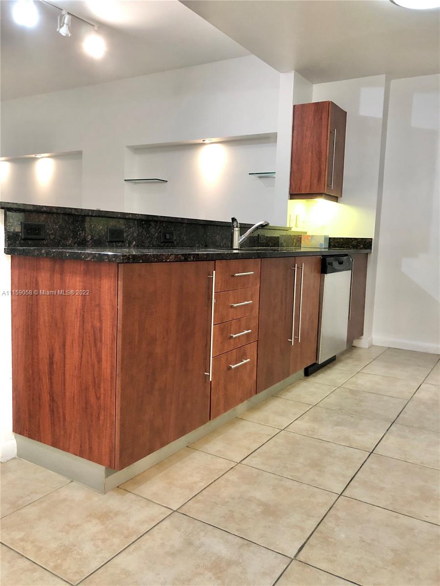 7371 Southwest 90th Street, Unit TH106S Miami, FL 33156 - Photo 2 of 25 a kitchen with granite countertop a stove a sink and a microwave