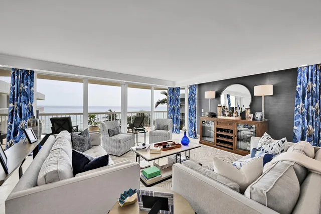 a living room with furniture a fireplace a large window and a potted plant