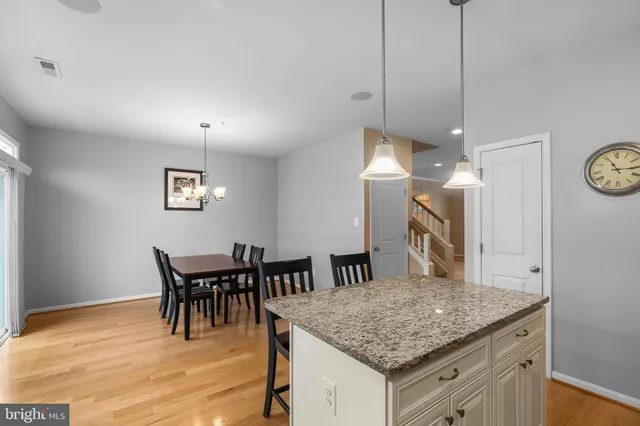 a kitchen with stainless steel appliances kitchen island granite countertop a dining table chairs and a refrigerator