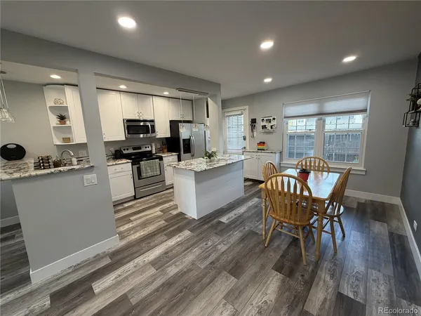 a kitchen with a table chairs wooden floors and a view of living room