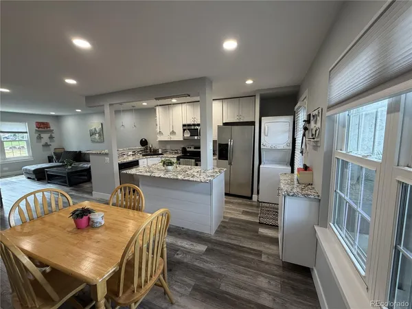 a kitchen with refrigerator a stove and a dining table with wooden floor
