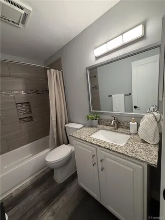 a bathroom with a granite countertop toilet sink and mirror