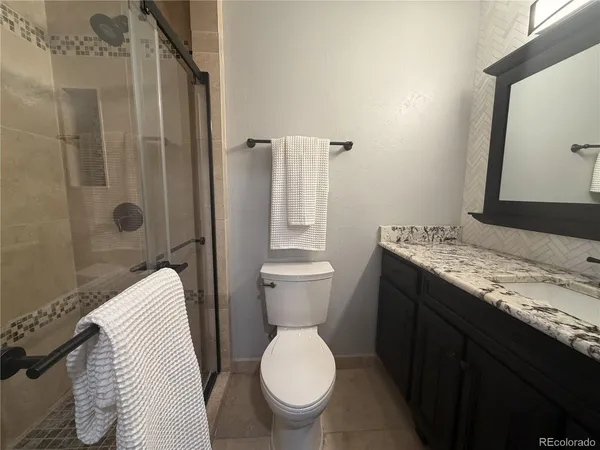 a bathroom with a granite countertop toilet and a sink
