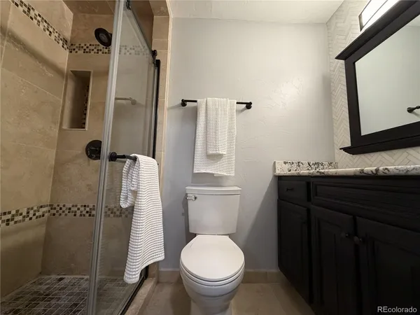 a bathroom with a granite countertop toilet sink and mirror